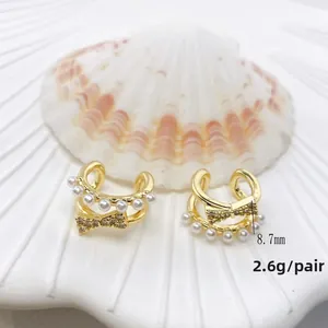 Makroaufnahme der goldenen Schleifen-Ohrmanschette mit Strasssteinen und weißen Perlen