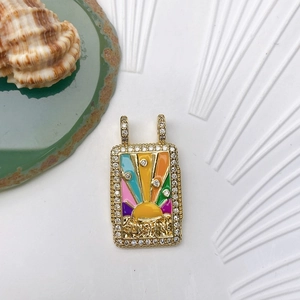 Detail of gold-plated rectangular sun pendant with colorful enamel and crystal accents