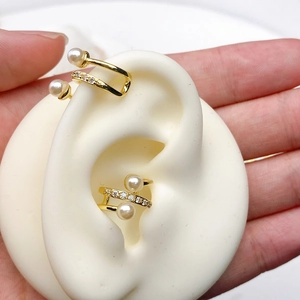 Close-up of gold-plated double-layer ear cuff with pearls and zircons on ear model