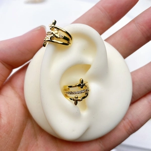 Detail of gold U-shaped ear cuffs with clover motifs and pavé cubic zirconia