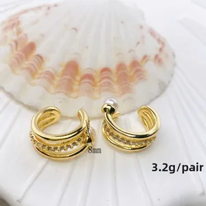 Makroaufnahme goldener Ohrmanschetten mit Zirkonia-Inlay und weißem Perlendetail