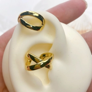 Detail of 18K gold plated wavy and cross ear cuff set with high polish finish on a model
