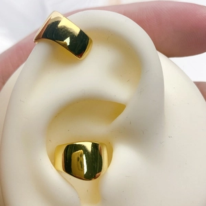 Macro detail of wave-shaped 18K gold-plated ear cuffs on a silicone ear model