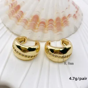 Details von 8,8 mm goldenen C-Ohrklemmen mit Zirkonia-Besatz auf einer Muschel