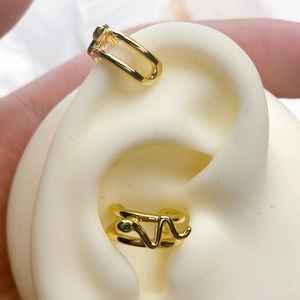 Detailed view of snake-shaped ear cuff with green gemstone and minimalist gold band