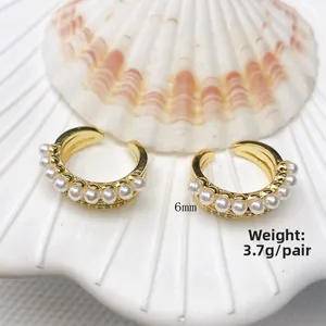 Macro detail of elegant double C-shaped gold ear cuffs with pearls and zircon accents
