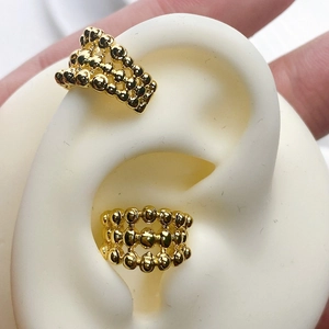 Detailed close-up of golden beaded layered ear cuff on a white silicone ear model