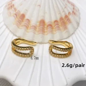 Detail of 18K gold-plated double C ear cuffs with white zircons on a seashell