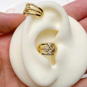Detail of clover-shaped gold ear cuff set with white crystals on a silicone ear model