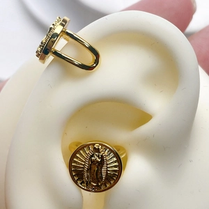 Macro detail of 18K gold plated ear cuff with religious Virgin Mary pendant carving