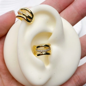 Detail of gold-plated multi-layer ear cuff with cubic zirconia on a white ear model