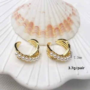 Macro detail of gold plated pearl ear cuff featuring triple-layered wave design on seashell