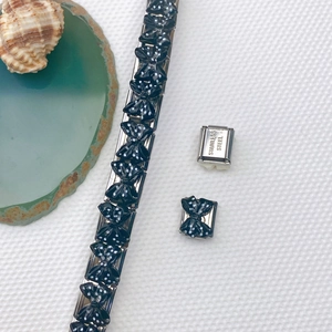 Makroaufnahme von Edelstahl-Charm-Armband-Gliedern mit Gravurdetail auf der Rückseite