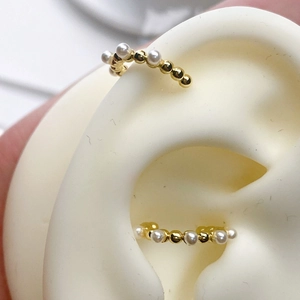 Detailed close-up of 18K gold plated pearl ear cuffs on a silicone ear model