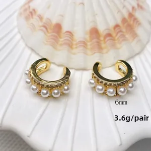 Detailed close-up of C-shaped 18K gold-plated earring with white pearls and zircons