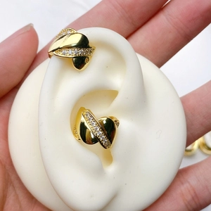 Detail of gold U-shaped ear cuff with sparkling zircon inlay on white silicone ear model
