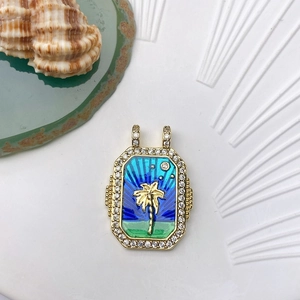 Detail of a gold palm tree pendant with blue enamel and sparkling pavé crystals