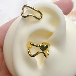 Close-up of gold-plated heart and wavy ear cuff set worn on a silicone ear model