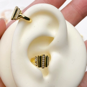 Macro shot of gold U-shaped ear cuff with zircon rectangular bars on ear model