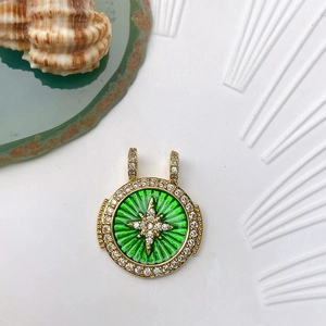 Detailed macro view of gold round sunburst charm with green enamel and crystal star