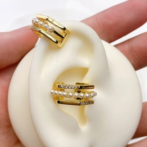 Detail of gold U-shaped ear cuffs with white pearls and sparkling cubic zirconia stones