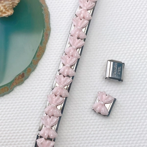 Detailaufnahme von italienischem Charm-Armband mit rosa gepunkteter Schleife aus Edelstahl