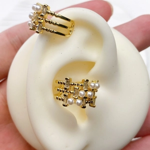 Detail of U-shaped gold cuff earring with round pearls and baguette-cut zircons