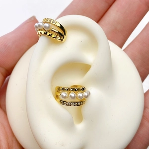 Detail of gold U-shaped ear cuff with pearls and zircons on a white model ear