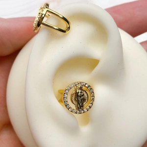 Macro detail of U-shaped gold ear cuff featuring paved white zircons and religious relief
