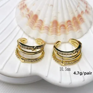 Macro detail of 18K gold plated star ear cuffs with zircons on a white shell prop