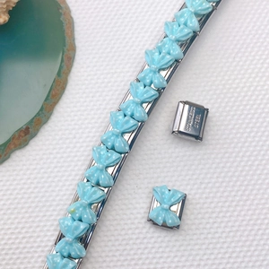 Detail eines italienischen Bettelarmbands mit hellblauen Schleifen auf Edelstahlgliedern