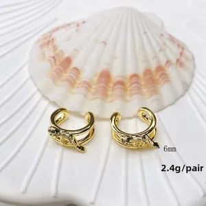 Detail view of U-shaped ear cuffs with green gemstones and animal motifs on a shell base