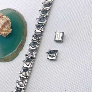 Détail macro du bracelet à breloques italien en acier avec motif gothique de croix R.I.P.