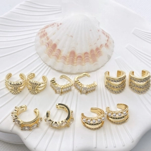 Set of five elegant gold-plated ear cuffs with sparkling zircons and pearls displayed on shell