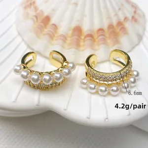 Detail of U-shaped gold ear cuff with white pearls and micro-pave zircons on a shell