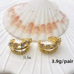Close-up of golden triple-layered ear cuff with white rhinestones on shell background