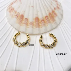 Detail view of U-shaped gold ear cuffs with 4mm cubic zirconia stones on textured background