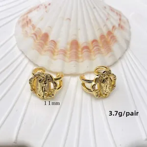 Detailed close-up of golden U-shaped ear cuffs with Virgin Mary relief and rhinestones