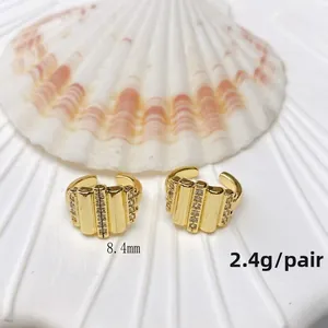 Detail view of U-shaped gold ear cuffs with vertical stripes and white zircon inlays