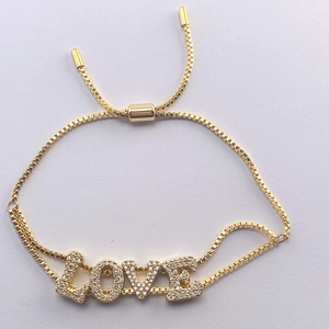 Detail of adjustable gold LOVE charm bracelet with sparkling crystals and box chain