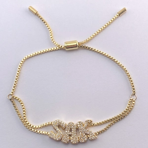 Detail of adjustable gold box chain bracelet with sparkling SAK pavé crystal letter pendants