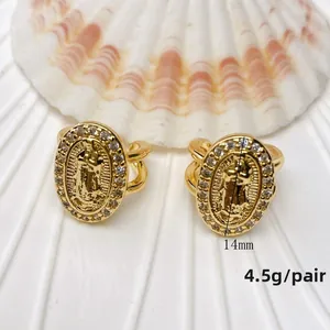 Detail view of gold Virgin Mary medallion earrings with cubic zirconia and U-shaped design