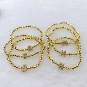 Pulsera elástica de cuentas doradas con colgante de letra de circonitas micro-pavé