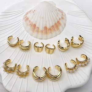 French U-shaped gold ear cuff set with pearls and zircons displayed on shell tray