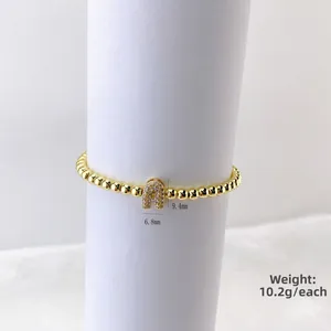 Pulsera de cuentas de oro pulido con dije de letra A en circonita sobre fondo blanco puro