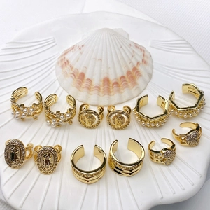 French U-shaped gold ear cuffs and rings set with pearls and zircons in a shell tray