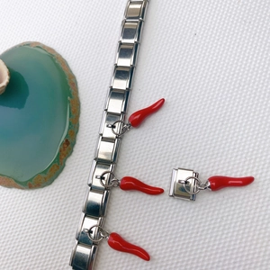 Détail d'un bracelet italien avec un pendentif piment rouge sur des maillons en acier inoxydable