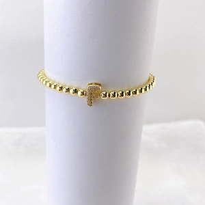 Pulsera elástica de cuentas doradas con dije de letra F pavonado en circonita brillante