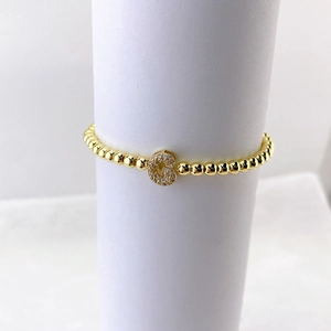 Detalle de una pulsera elástica de cuentas doradas con un colgante pavé de cristales