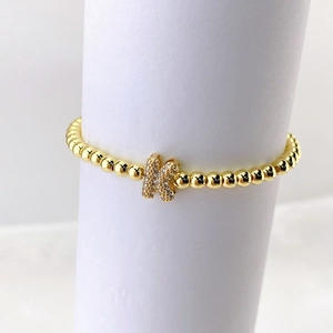 Primer plano de pulsera de cuentas doradas con dije de mariposa brillante de circón